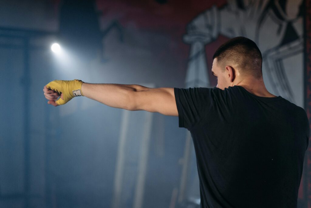 Man in a gym practicing boxing techniques with yellow hand wraps, perfect for fitness inspiration.
